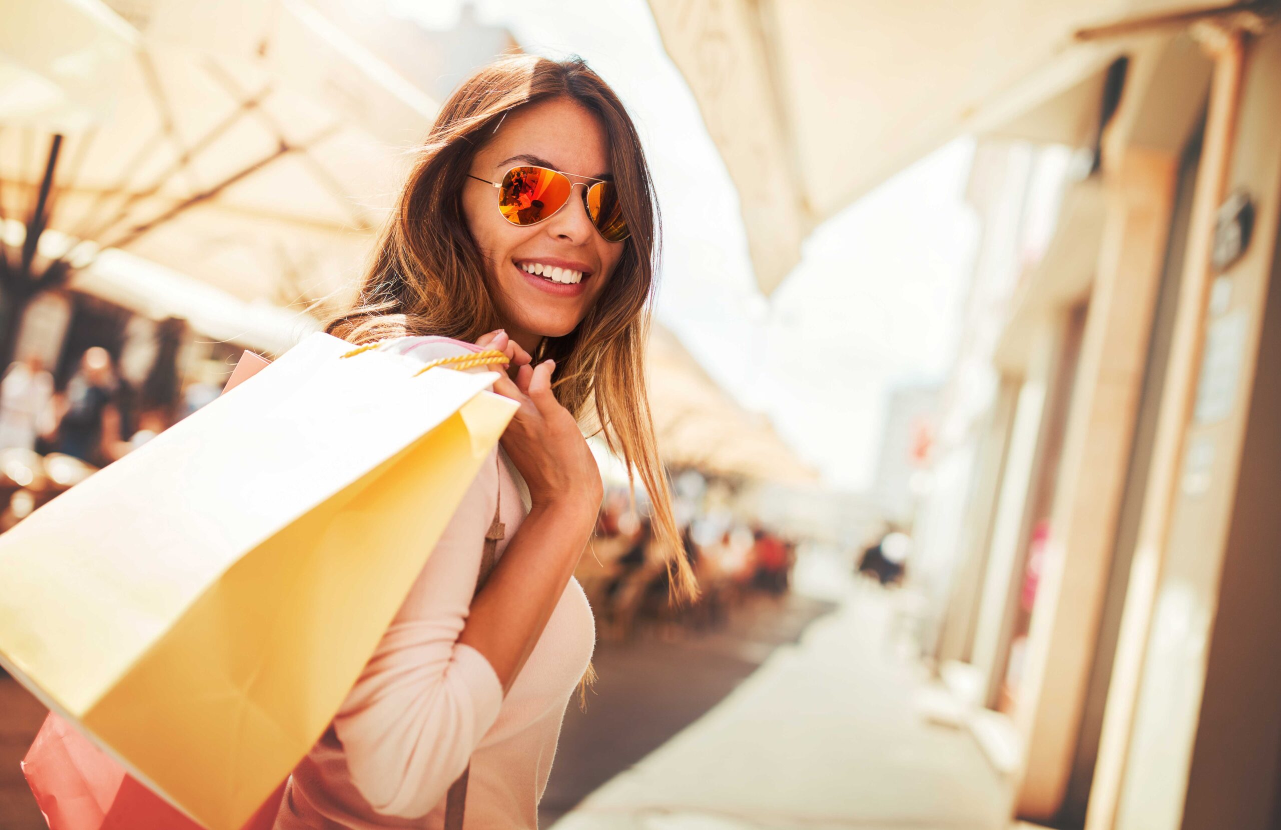 Woman with aviator sunglasses with shopping bags over her shoulder in a market
