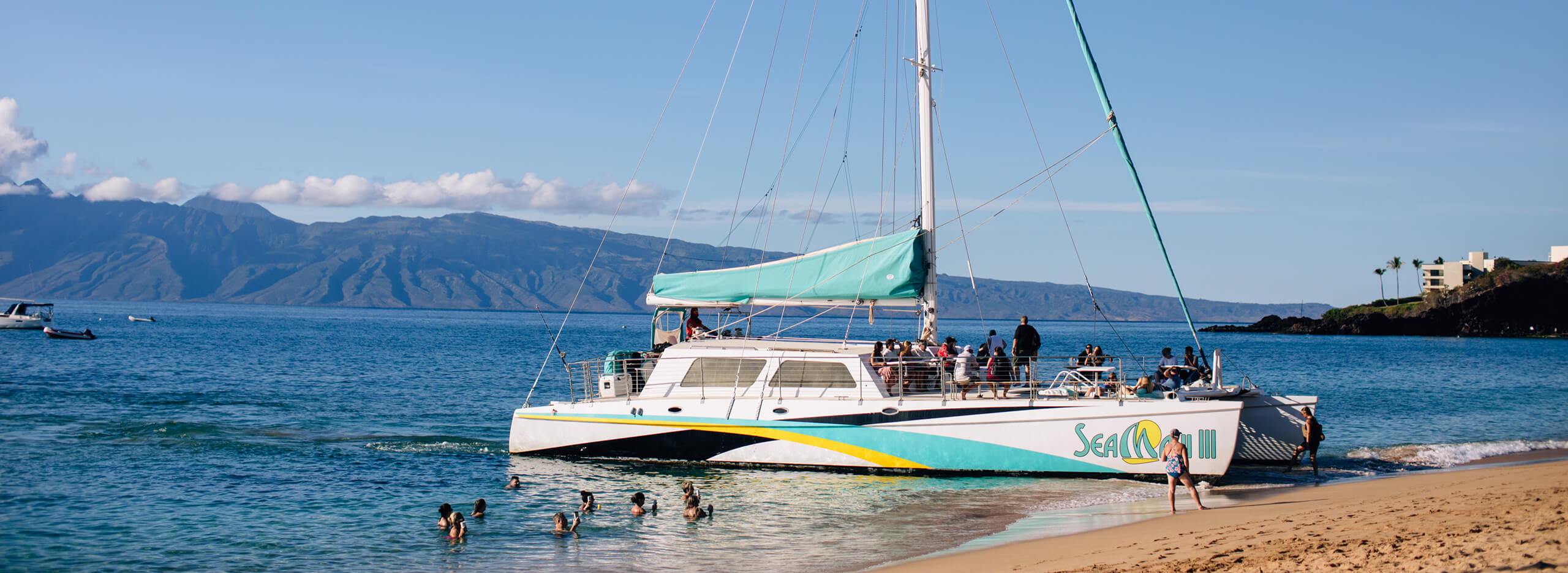 Boat cruise on shore with people swimming around
